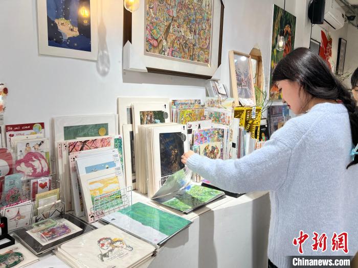 圖為藝術(shù)品商店內(nèi)，顧客挑選插畫作品?！＄婌?攝