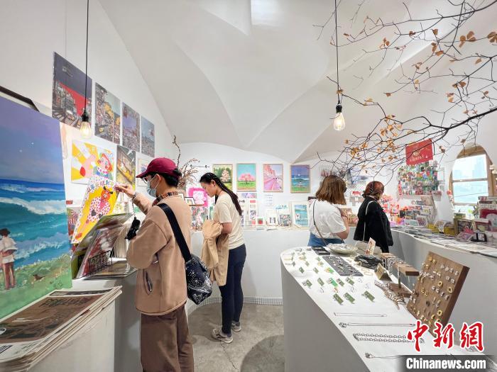 圖為藝術(shù)品商店內(nèi)，顧客挑選插畫作品?！＄婌?攝