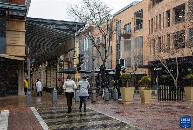 7月10日，在南非約翰內(nèi)斯堡一處商業(yè)區(qū)，人們在雪中行走。新華社記者 張譽東 攝