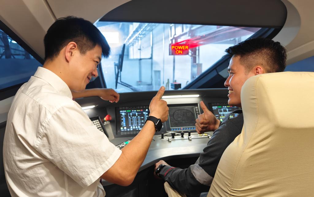 8月25日，在印度尼西亞萬隆的雅萬高鐵德卡魯爾動(dòng)車所內(nèi)，中國師傅穆振（左）在向印尼火車司機(jī)塞蒂亞萬講解動(dòng)車組出庫前的上電作業(yè)。