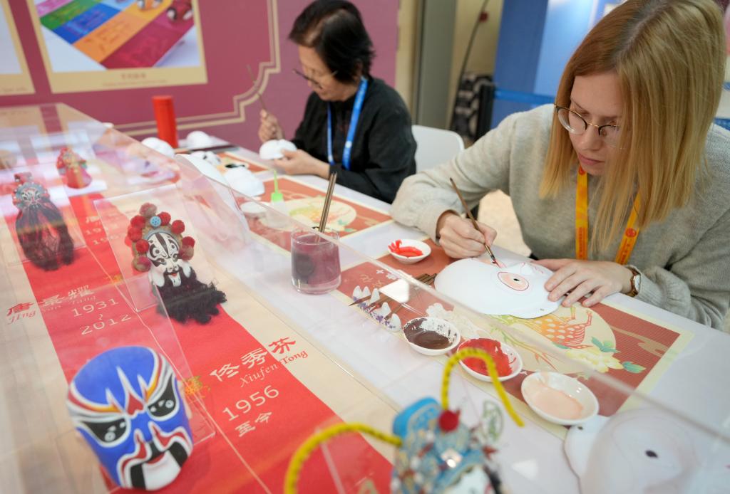 10月16日，在第三屆“一帶一路”國(guó)際合作高峰論壇新聞中心，來自比利時(shí)的記者（右）體驗(yàn)畫京劇臉譜。新華社記者 王毓國(guó) 攝