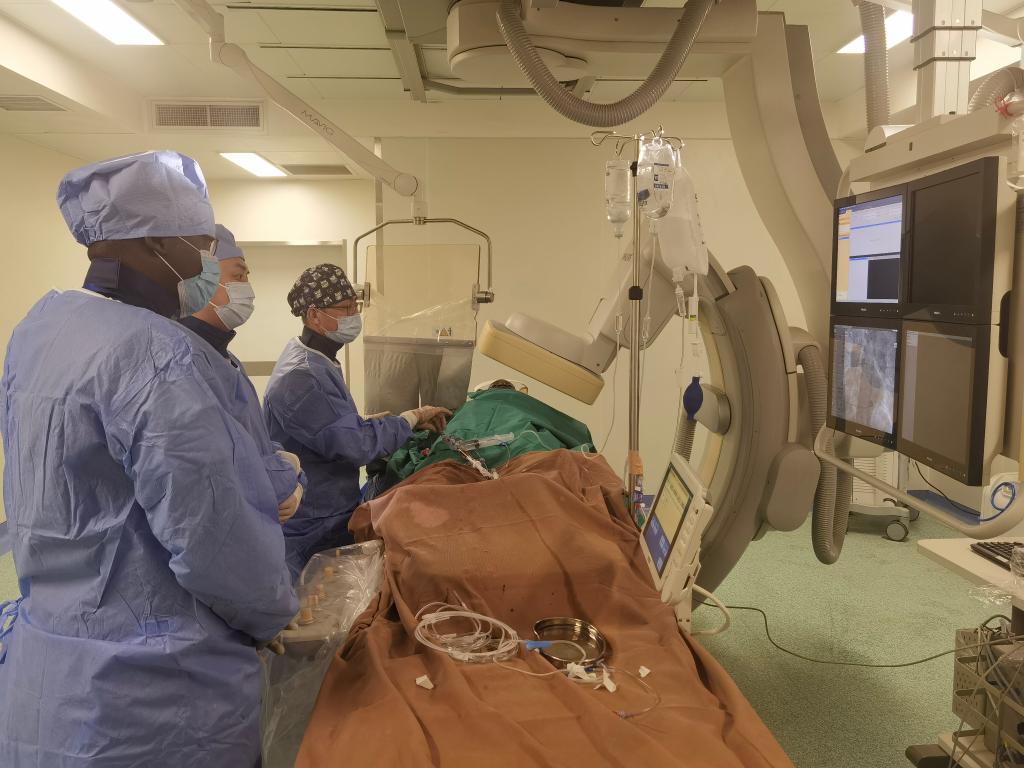 中國第29批援幾內(nèi)亞醫(yī)療隊(duì)隊(duì)員、首都醫(yī)科大學(xué)附屬北京天壇醫(yī)院心內(nèi)科副主任醫(yī)師王汝朋（右一）正在給患者做手術(shù)。（北京天壇醫(yī)院供圖）
