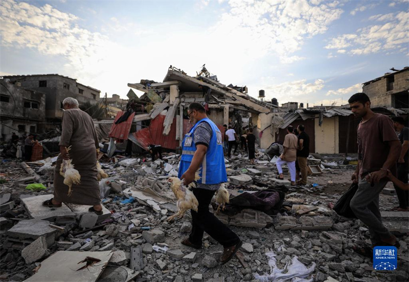 10月27日，在加沙地帶南部城市汗尤尼斯，人們經(jīng)過以軍襲擊后的房屋廢墟。