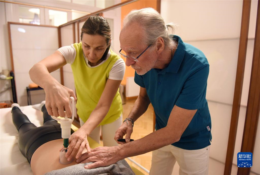 12月12日，在奧地利維也納，科格勒醫(yī)生（右）和助手在為病人進行拔罐治療。新華社記者 賀燦鈴 攝
