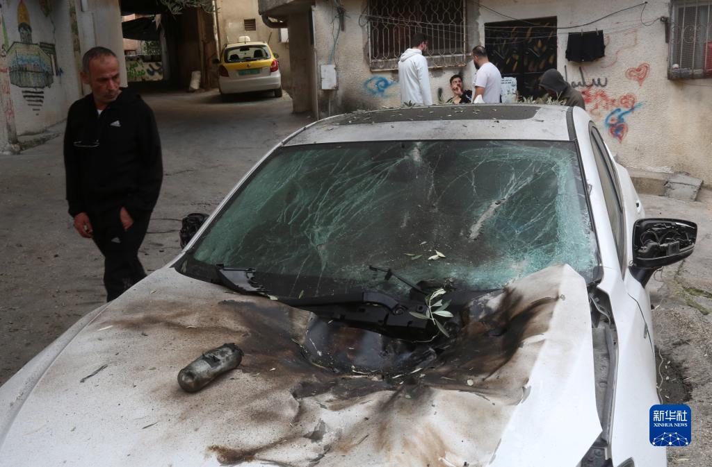 12月17日，在約旦河西岸城市圖勒凱爾姆附近的一處難民營，人們查看在沖突中損毀的車輛。新華社發(fā)（尼達(dá)爾·艾仕塔耶?dāng)z）
