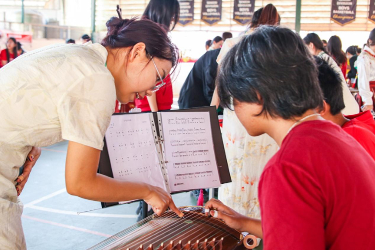 志愿者教師指導(dǎo)學(xué)生彈奏古箏。活動(dòng)主辦方供圖