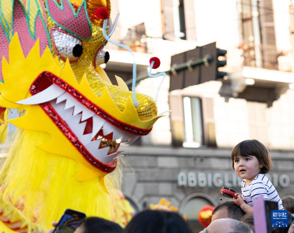 2月18日，在意大利羅馬，一名小朋友在彩妝巡游上觀看舞龍。新華社記者 李京 攝