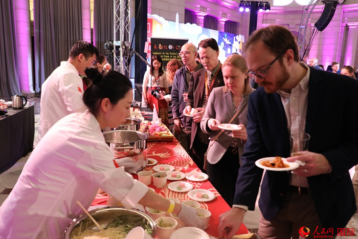 當?shù)貢r間3月7日晚，華盛頓聯(lián)合車站廣場舉行駐美使團“使館主廚挑戰(zhàn)賽”。圖為當?shù)孛癖娫谥袊古_前體驗中國美食。人民網(wǎng)記者 李志偉攝