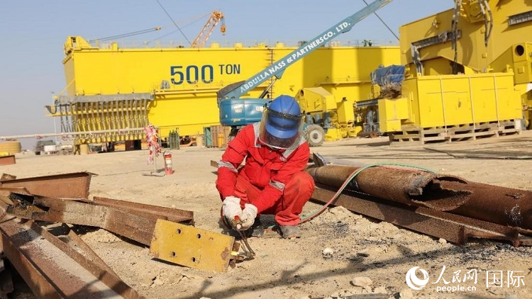 工人正在龍門吊吊裝現(xiàn)場切割金屬件。人民網(wǎng)記者管克江攝