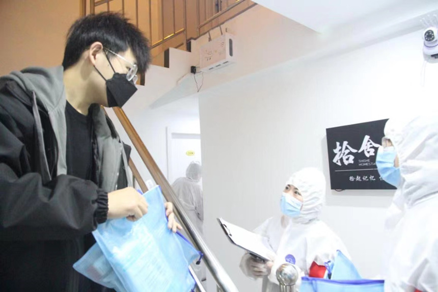 社區(qū)工作人員和志愿者身穿防護(hù)服上門送馬應(yīng)龍大健康防疫包。徐帥攝