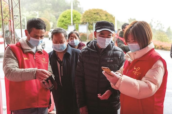 長(zhǎng)沙縣黨員志愿者正在幫助參與核酸檢測(cè)的群眾掃描“場(chǎng)所碼”。劉思源 攝