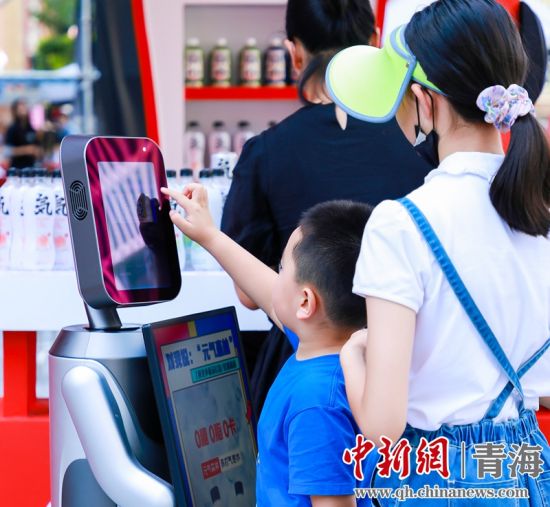 圖為一名小朋友正在和機(jī)器人“志愿者”進(jìn)行互動。 沐聞 攝