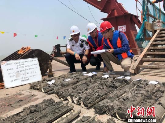 圖為勘察設(shè)計人員與海事局工作人員查看巖芯情況?！∥赫?攝