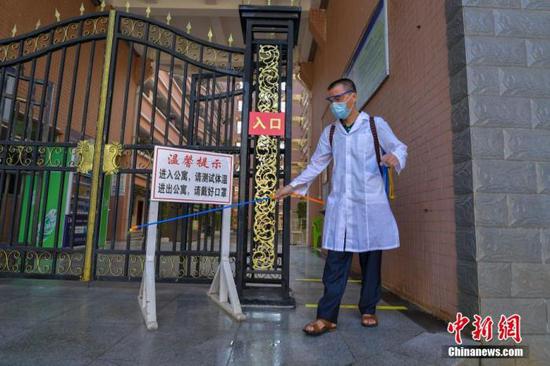 資料圖：海口經(jīng)濟(jì)學(xué)院的工作人員在學(xué)生宿舍樓入口消毒。 中新社記者 駱云飛 攝