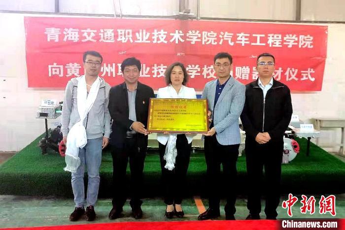 圖為李富香(中)代表學(xué)校為州縣技校捐贈器材。(資料圖) 青海省教育廳供圖