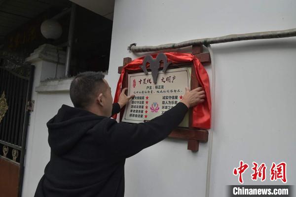 桂溪鎮(zhèn)渭溝村政府工作人員為“十星級文明戶”掛上牌匾?！钣?攝