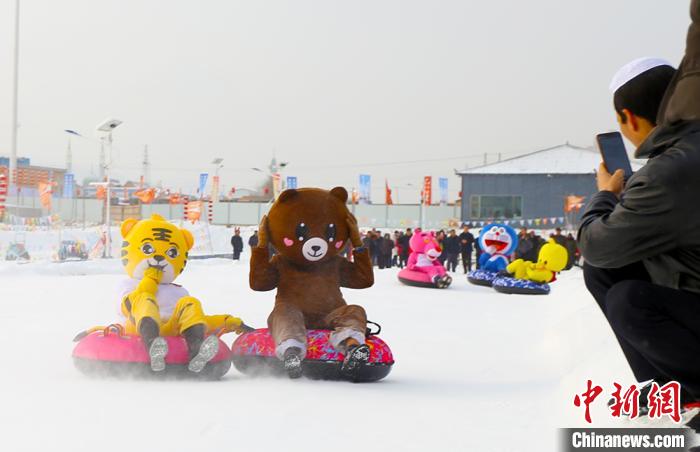 圖為臨夏市南龍鎮(zhèn)馬家莊村舉辦的鄉(xiāng)村文化旅游節(jié)上，游客穿著卡通服裝在體驗雪上飛碟項目。近年來，臨夏州形成了“春賞花、夏避暑、秋摘果、冬玩雪”的全季節(jié)旅游產(chǎn)品體系。(資料圖) 高展 攝