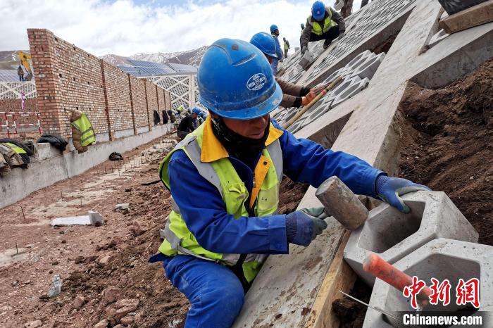 圖為光伏發(fā)電項(xiàng)目施工區(qū)工人在護(hù)坡鋪設(shè)空心磚。　李雋 攝