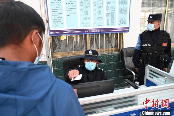 圖為移民管理警察登記完身份信息后將證件歸還給行人?！≮w朗 攝