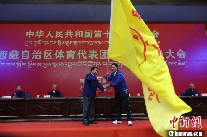 西藏自治區(qū)副主席甲熱·洛桑丹增授代表團團旗，西藏自治區(qū)體育局局長尼瑪次仁接旗?！∪轿木?攝