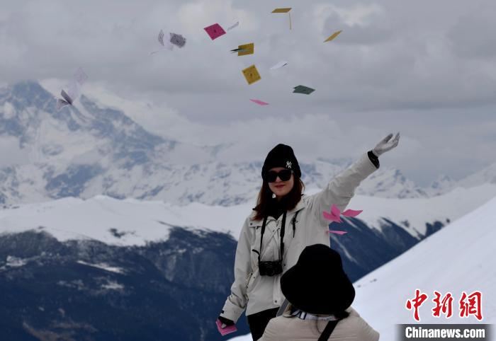 圖為5月14日，游客在西藏林芝色季拉山觀景臺拋灑“隆達”(風(fēng)馬旗，藏族民眾的一種祈福方式)?！±盍?攝